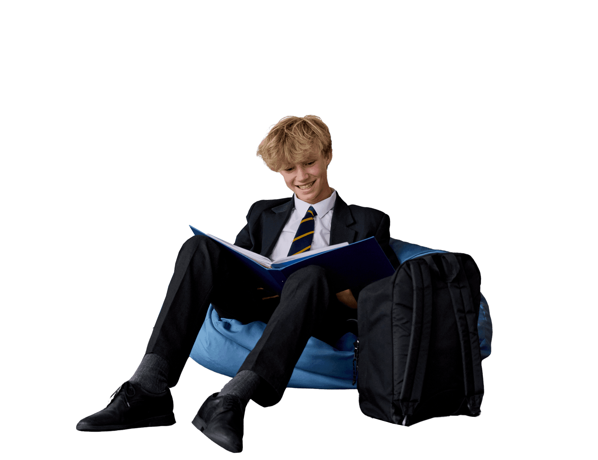 Smiling student in school uniform sits on a blue beanbag, reading an open book.